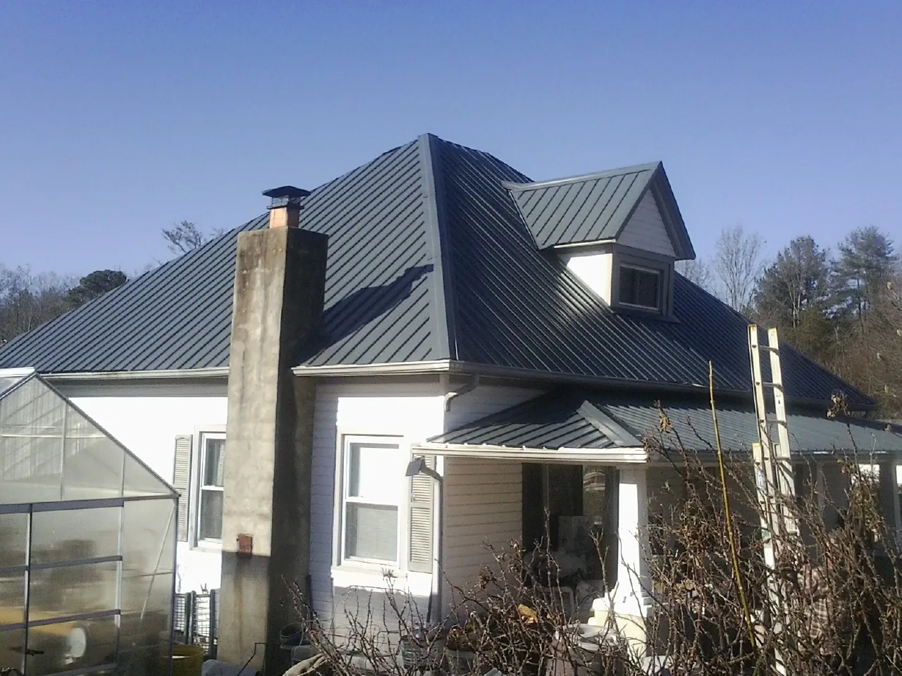 Dark blue standing seam metal roof on a white farmhouse with dormer — Slate & Tile Roof Repair by Roofing Brothers in Mount Juliet