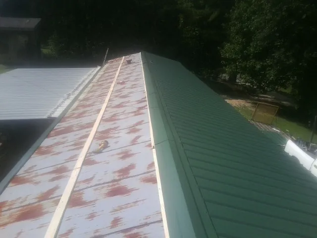 Old rusted panels beside newly installed green metal roofing — Wind Damage Roof Repair by Roofing Brothers in Mount Juliet