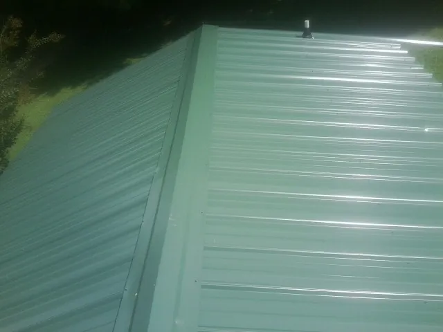 New green metal panels meeting at the ridge of a roof — Flat Roof Repair work by our crew in Mount Juliet
