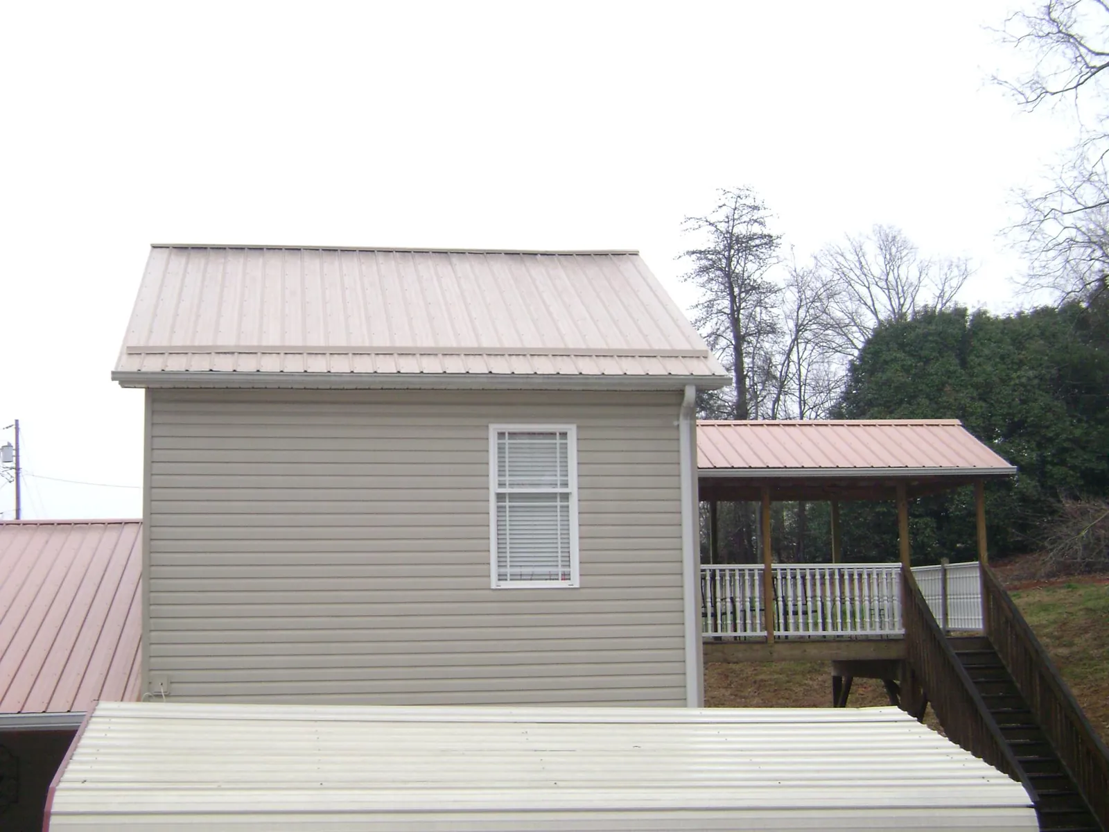 Tan metal roofs on a two story addition and attached porch, from a Roof Replacement job in Mount Juliet