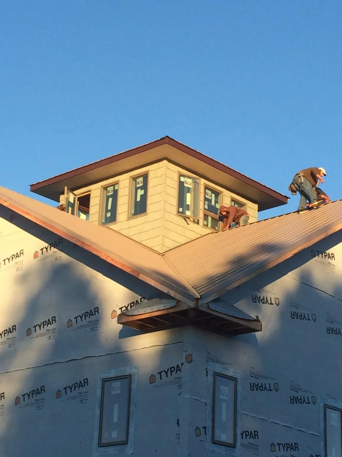 Roofers working around a rooftop cupola on a new metal roof at sunset — Roof Waterproofing in Mount Juliet by Roofing Brothers